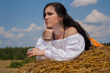 young woman in ethnic dress sitting on a haystack