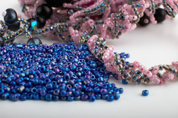 Multi-colored beads.Colorful beads on a wooden surface.It is used in finishing fashion clothes.Variety of shapes and color to make abead necklace or a string of beads toplease a woman of fashion.