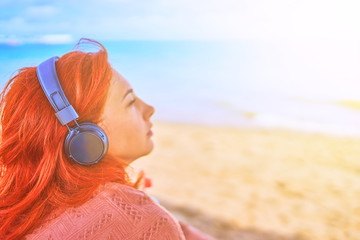 Beautiful woman listening to music on the beach.