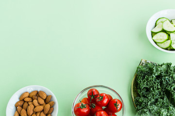 Vegetables and nuts on a light green background. Cherry tomatoes, cabbage cale, cucumbers and almonds. The concept of diet. Space for text