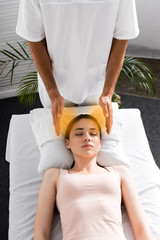 woman lying on massage table with closed eyes while healer cleaning her aura
