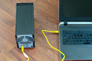 Laptop connected with NAS network device with yellow ethernet cable
