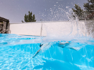 Man throws himself into the pool in a split view of water and air