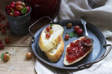 Toasts with gooseberry jam and gooseberries on a tin tray. Rustic style.