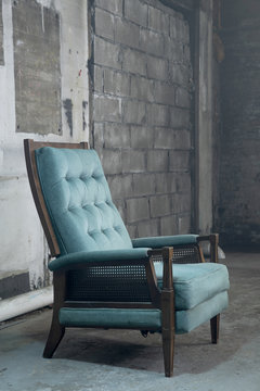 Blue velvet chair next to cinderblock wall