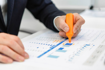 Close-up of businessman using highlighter on a report at desk in office