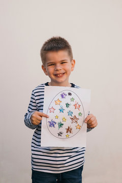 Boy holding his art work and smiling