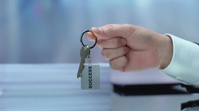 Businessman hand showing keychain to camera, self-motivation methods, success