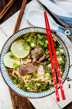 Bowl of Vietnamese Pho with rice noodles, mung beans, cilantro, spring onions and limes