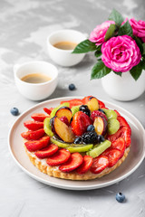 Tart with strawberries, kiwi, plums and cream