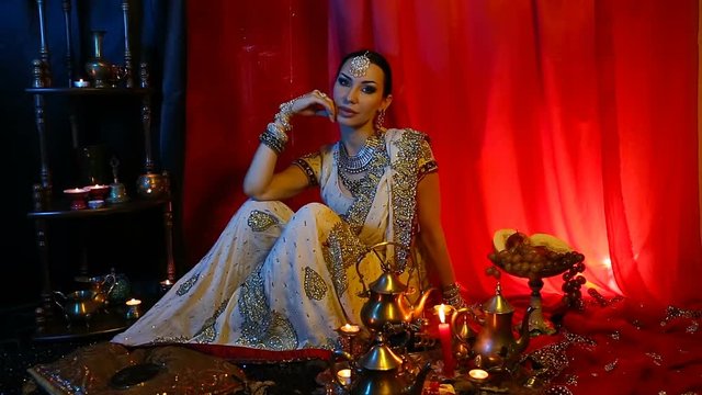 Beautiful young indian woman in traditional Sari clothing and Oriental Jewelry.