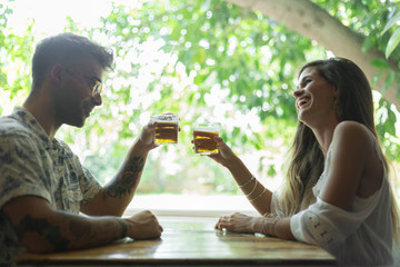 Happy young couple clinking beer glasses at the table of a restaurant