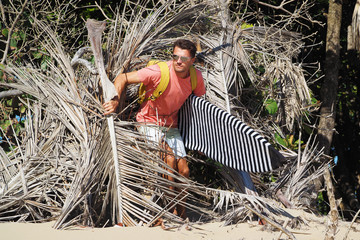 A man surfer with a surfboard out of the hut. Beach surf spot.