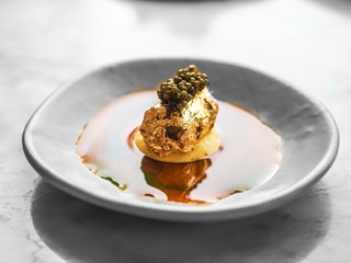 Closeup of a golden wrapped food with sauce and caviar on top