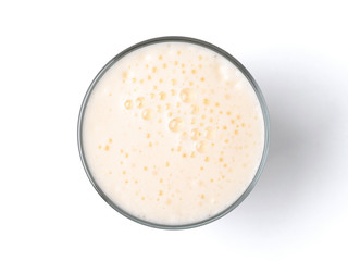Vanilla milkshake with foam isolated on white. Delicious milk dessert with vanilla in glass isolated on white with clipping path. Top view or flat lay.