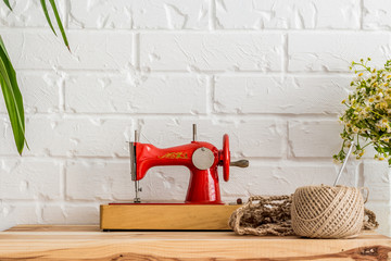 Red sewing machine on a wooden table. Sewing industry. Diy