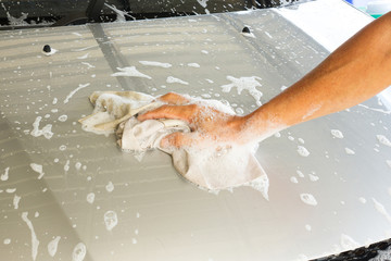 Car washing. Closeup man hand use cloth washing front of car. Transportation background.