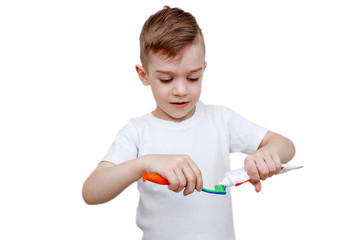 little boy in white t-shirt squeezes toothpaste on brush. Health care, hygiene and childhood concept. Caries prevention