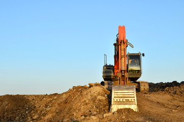Excavator at a construction site during earthworks and laying of underground pipes. Professional excavation contractor serving, trenching, grading for residential, commercial, and municipal projects