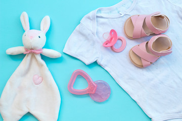 Baby clothes, shoes, teether and pacifier on a blue background