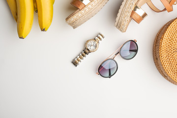 Wicker fashion bag, tropical bananas, sunglasses, and expensive watches Summer fashion, holiday concept.On a white background
