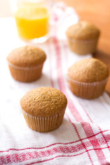 Fresh orange flavored cupcakes on a table with orange juice