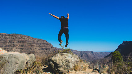 Man jumping whit arms raised in the mountain, feeling of freedom, lifestyle concept.