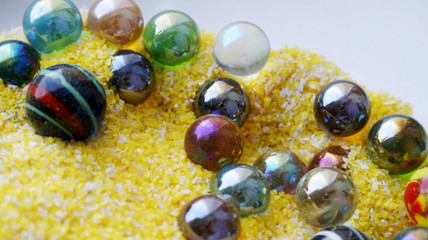 bright background beautiful colorful glass balls in yellow with pink and white sand
