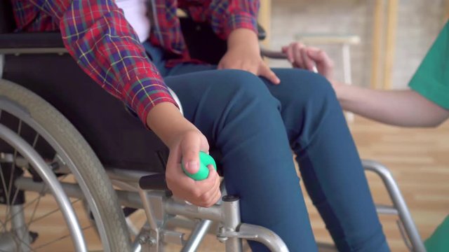 teenage girl is undergoing rehabilitated by a doctor after a hand injury with the help of a wrist expander close up