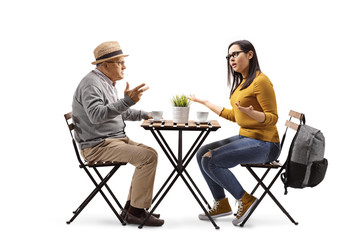 Angry female student in a cafe sitting at a table and arguing with an elderly man