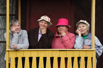 Four Russian elderly women are standing on the porch of their home. Close friends. Friendship. Country life.
