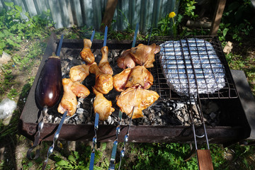 On skewers chicken skewers with vegetables are cooked on the fire.