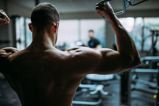 Young man doing chest exercise with cross machine.