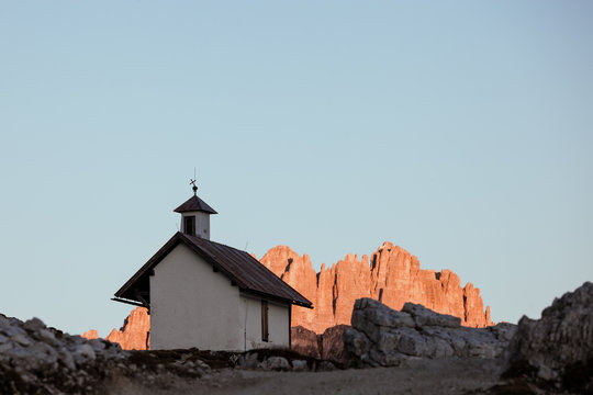 Mountain chapel with high rocky ridge on background at twilight. Tre Cime di Lavaredo National Park, Dolomites, Italy