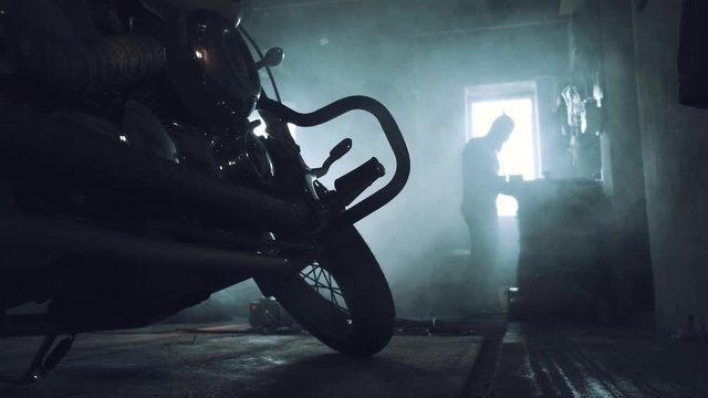 biker in the garage in the background something repairs on a workbench. foreground is his chopper