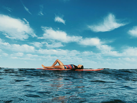 Full body portrait of female surfer lying on surfboard