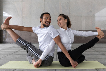 loving couple masters different nationalities conducts yoga practice near business center. Different asanas shanty yoga. concept possibility yoga in any urban space.