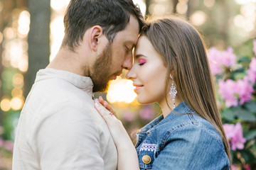 Sensual young couple enjoys tender warm pleasant kind moment of love having romantic date, affectionate beautiful man and woman touching foreheads caressing adoring each other in nature spring