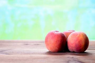 Three fresh peaches on a wooden table
