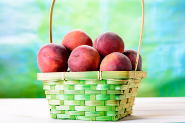 Fresh peaches on a wooden table next to the basket