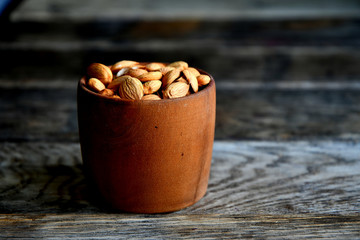 Almond nuts in a wooden bowl on the background of old boards.