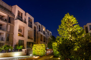 modern apartment houses in the night with green trees