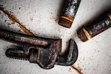 Rusty pipe wrench on white/grey texture background