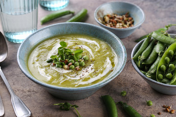 Green pea soup with croutons and micro greens sprouts on brown background