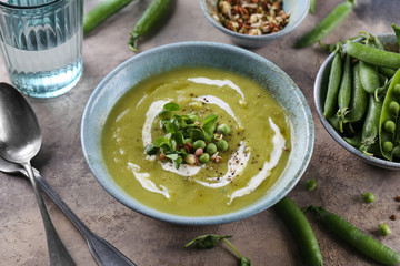 Green pea soup with croutons and micro greens sprouts on brown background