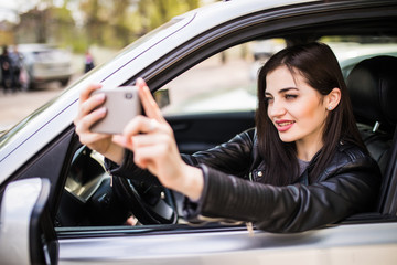 Young woman using cellphone to take photo inside a car