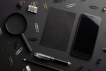 Flat lay, black style.Set of stationery accessories mock up on black background, phone, black card.