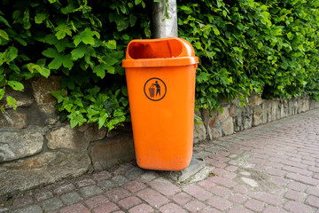 orange plastic trash can on a pole