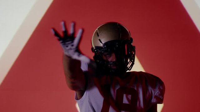 African American black football player posing against animation on a huge bright screen. Shot on ARRI Alexa Mini in 4K RAW