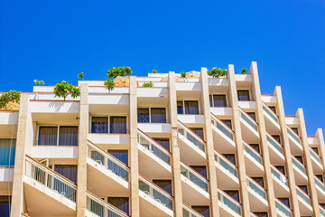 south hotel architecture exterior facade with windows and trees on roof terraces, renting apartment in summer vacation time 